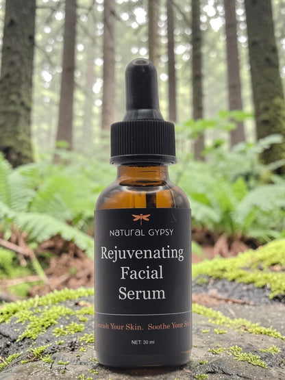 Natural Gypsy Rejuvenating Facial Serum in an amber glass dropper bottle, set on a mossy log in a forest.