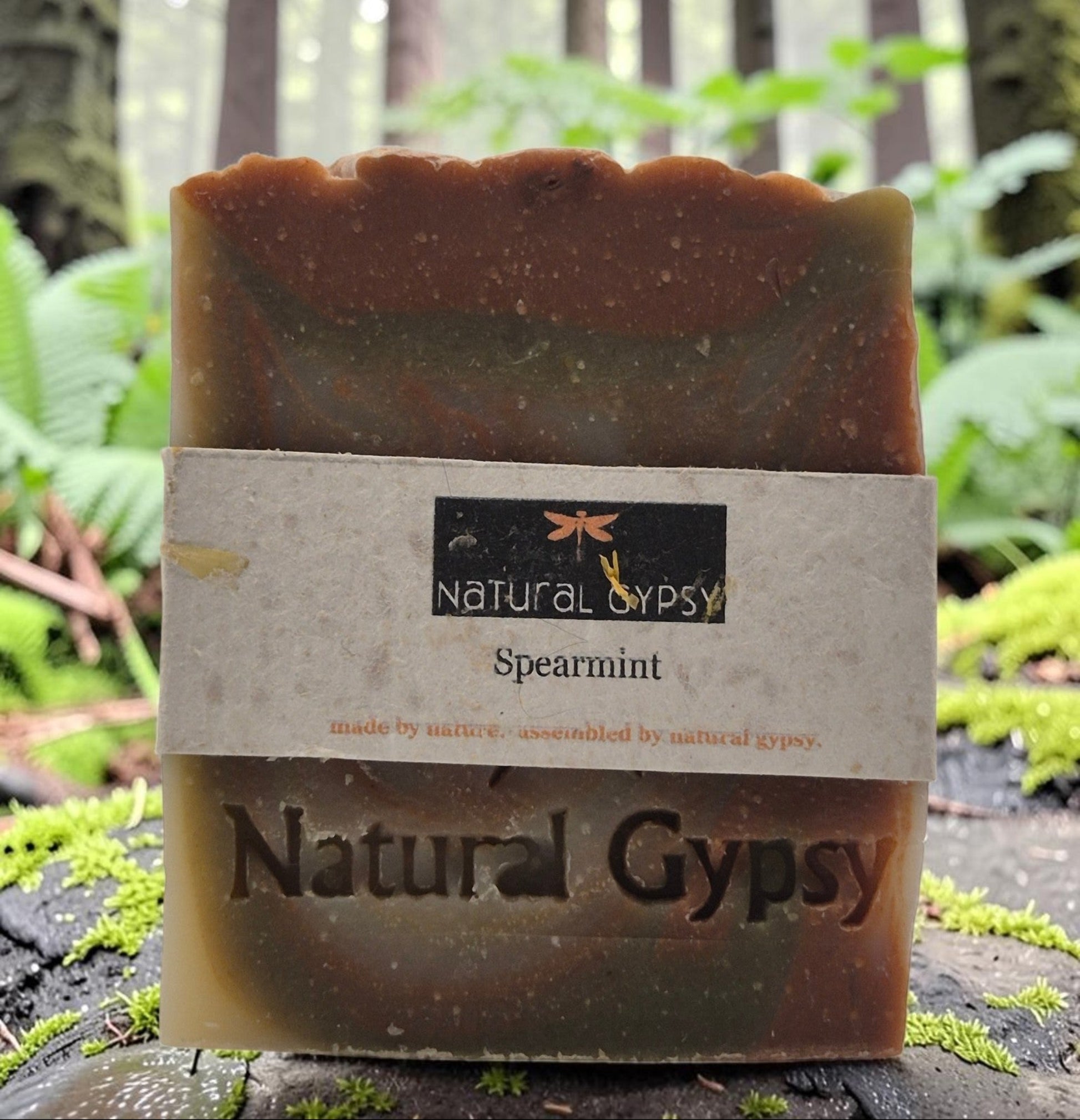 Natural Gypsy handcrafted spearmint artisan soap bar with earthy marbled texture, set against a misty forest background.