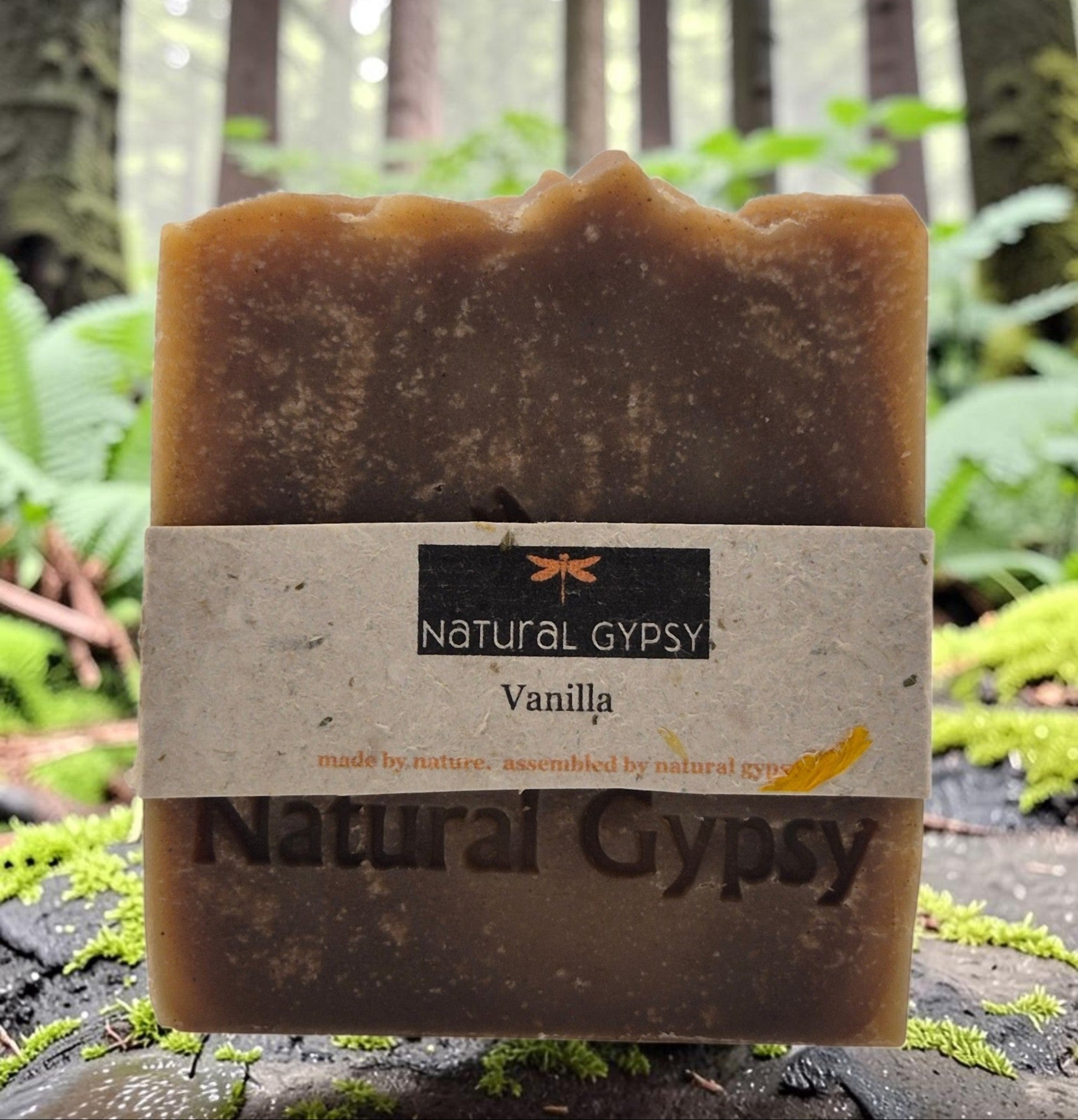 Natural Gypsy handcrafted vanilla artisan soap bar with rustic textured finish, displayed in a lush forest setting.